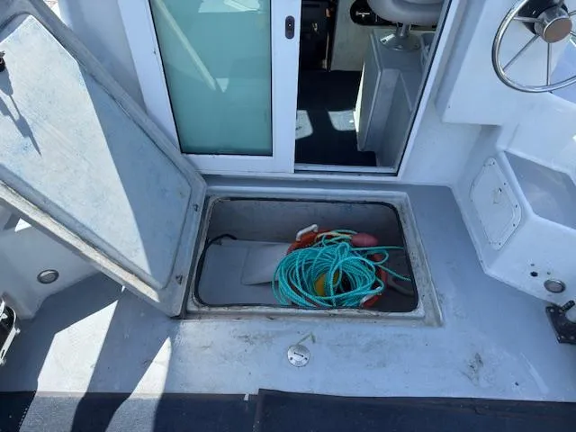 Slide: The Image of Open storage compartment on 2007 Radon Signature 26 boat with rope and equipment. - 12