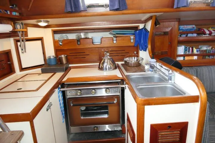 Slide: The Image of 1982 Cape Dory 36 yacht kitchen with stove, sink, and wooden cabinetry. - 13