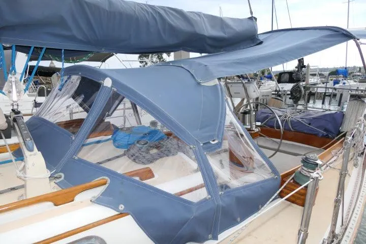 Slide: The Image of 1982 Cape Dory 36 sailboat with blue canvas cover in marina setting. - 32