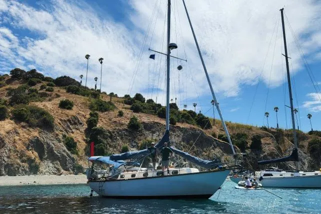 Slide: The Image of 1982 Cape Dory 36 sailboat anchored near scenic coastline with clear blue sky. - 57