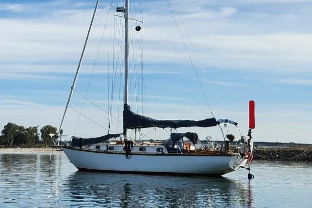 Slide: The Image of 1982 Cape Dory 36 sailboat anchored on calm water under a clear sky. - 58