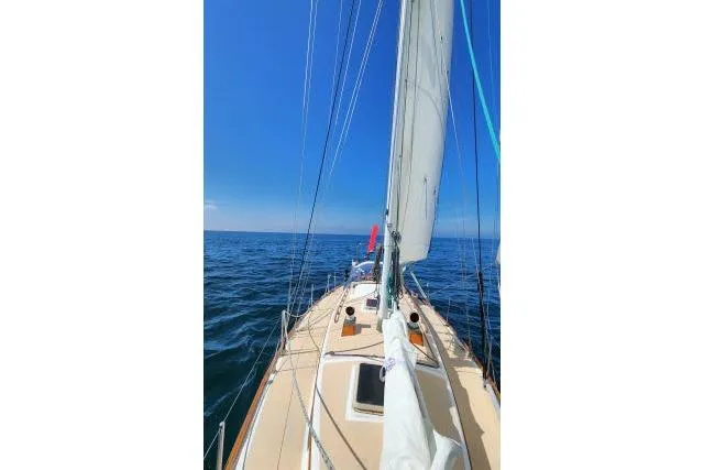 Slide: The Image of 1982 Cape Dory 36 sailboat navigating open sea under clear blue sky. - 62