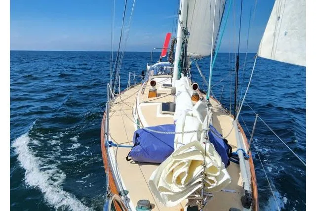 Slide: The Image of 1982 Cape Dory 36 sailboat navigating open sea under clear blue skies. - 63