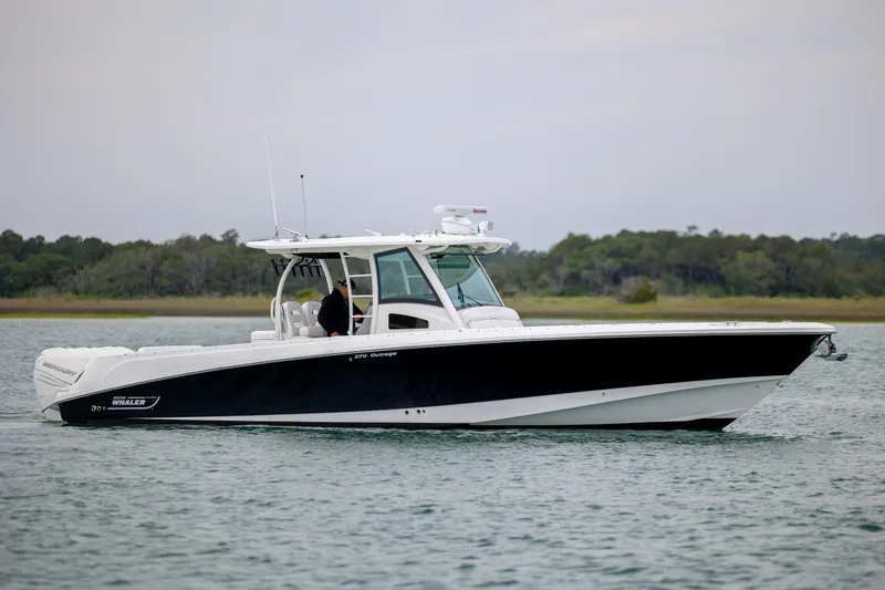 The Image of 2017 Boston Whaler 370 Outrage boat cruising on calm water with scenic background. - 1