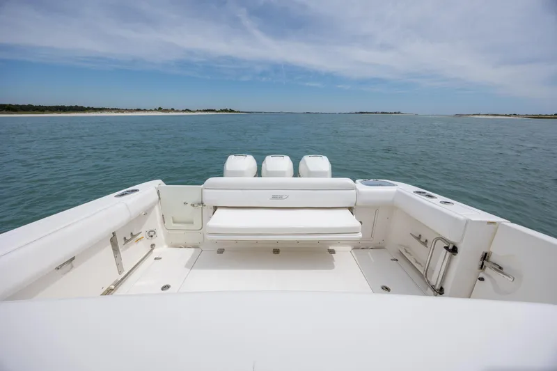 Slide: The Image of 2017 Boston Whaler 370 Outrage boat on calm waters, showcasing spacious deck and seating. - 17
