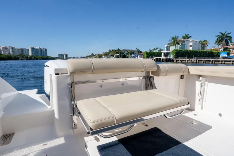Slide: The Image of 2018 Pursuit OS 325 Offshore boat with beige seating, docked by waterfront homes. - 17