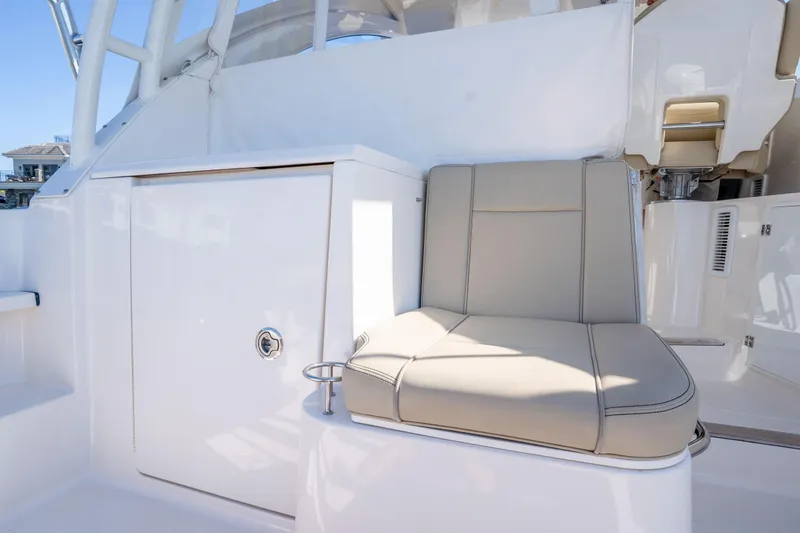 Slide: The Image of 2018 Pursuit OS 325 Offshore boat interior with beige seating and storage compartment. - 20