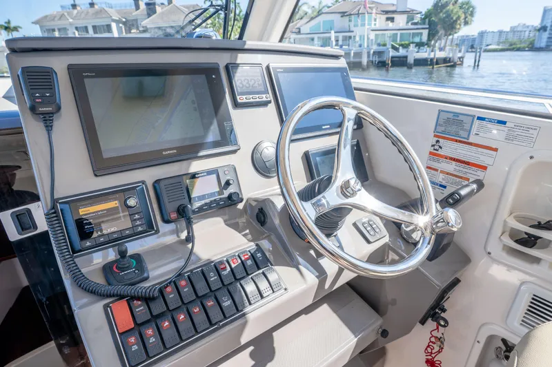 Slide: The Image of 2018 Pursuit OS 325 Offshore boat dashboard with navigation screens and controls. - 26