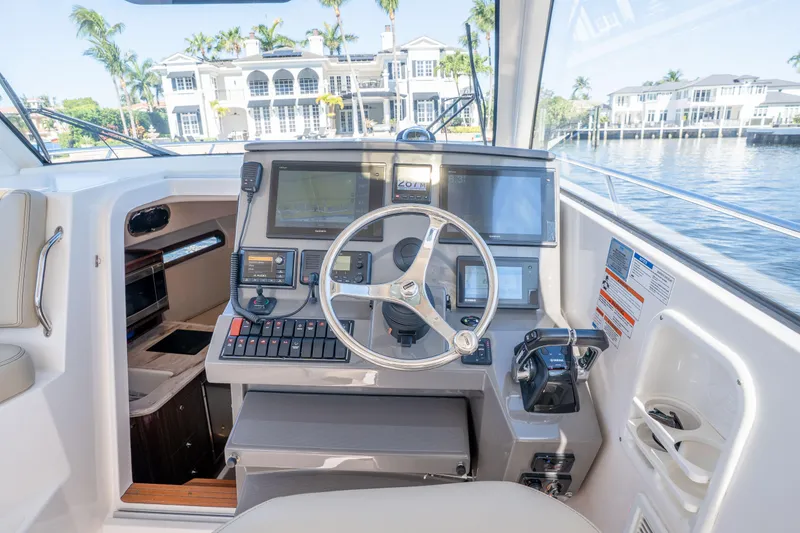 Slide: The Image of 2018 Pursuit OS 325 Offshore boat cockpit with modern navigation equipment and waterfront view. - 28