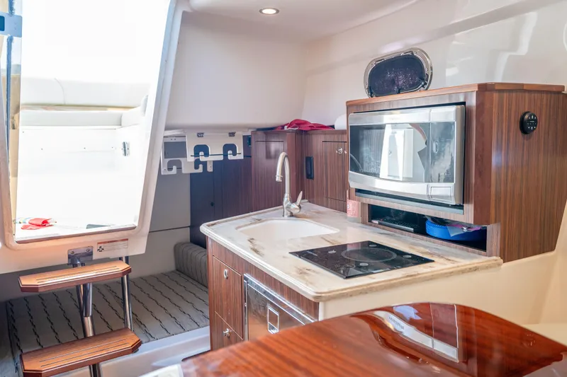 Slide: The Image of 2018 Pursuit OS 325 Offshore boat interior with kitchenette, microwave, and sink. - 29