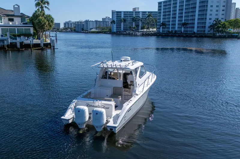 Slide: The Image of 2018 Pursuit OS 325 Offshore boat cruising in a scenic waterfront area. - 3