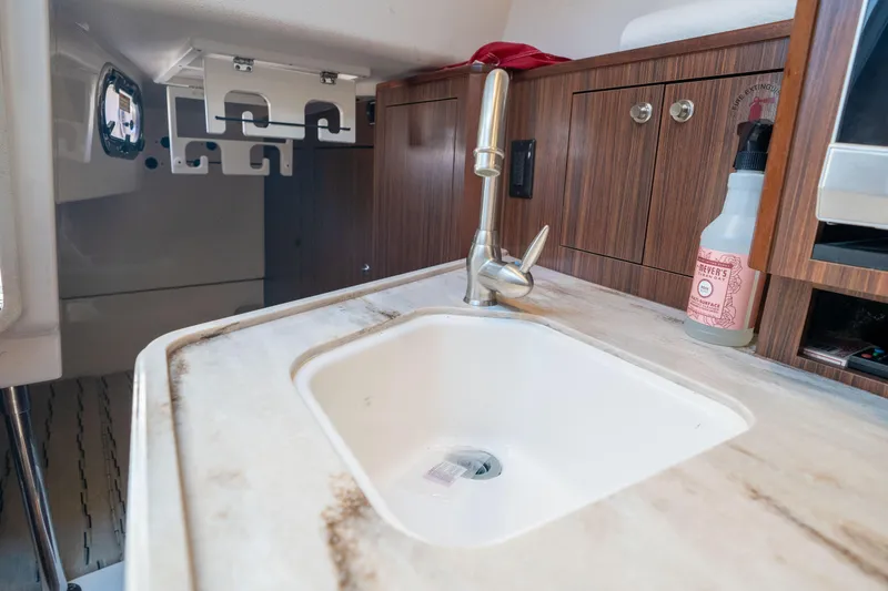 Slide: The Image of 2018 Pursuit OS 325 Offshore boat interior with sink and wooden cabinetry. - 33