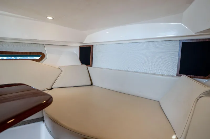 Slide: The Image of 2018 Pursuit OS 325 Offshore cabin interior with white seating and wooden accents. - 36