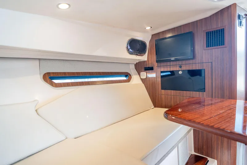 Slide: The Image of Interior of 2018 Pursuit OS 325 Offshore boat with seating, TV, and wood accents. - 37