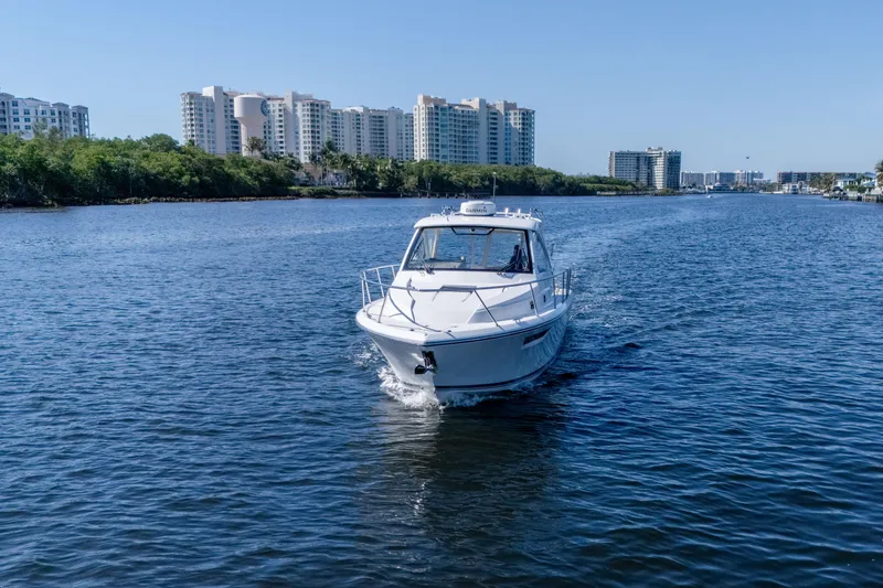 Slide: The Image of 2018 Pursuit OS 325 Offshore boat cruising on a scenic waterway with city skyline. - 4