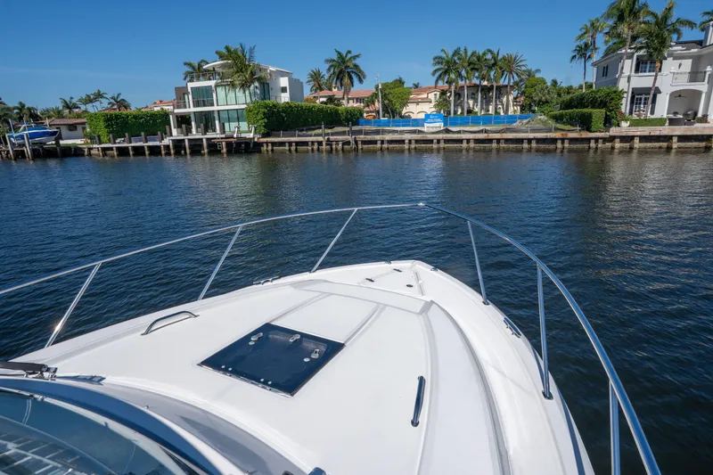Slide: The Image of 2018 Pursuit OS 325 Offshore boat cruising near waterfront homes and palm trees. - 43