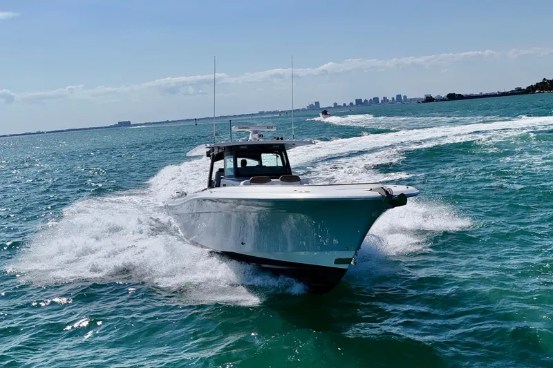 Slide: The Image of 2019 HCB 53 Suenos boat cruising on open water with city skyline in background. - 12