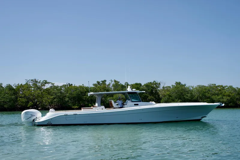 Slide: The Image of 2019 HCB 53 Suenos boat cruising on calm water near lush greenery. - 2