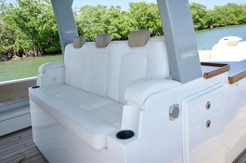 Slide: The Image of Luxurious seating on 2019 HCB 53 Suenos boat, featuring white upholstery and scenic water backdrop. - 23