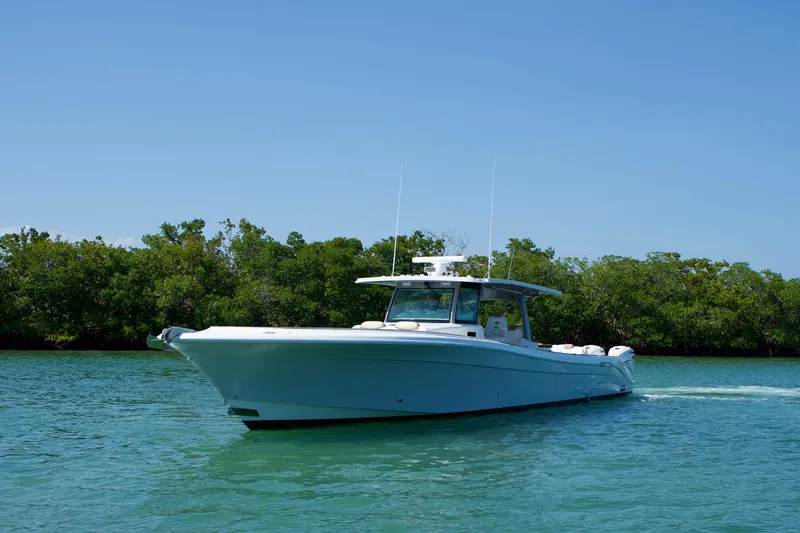 Slide: The Image of 2019 HCB 53 Suenos boat cruising on clear blue water near lush greenery. - 7