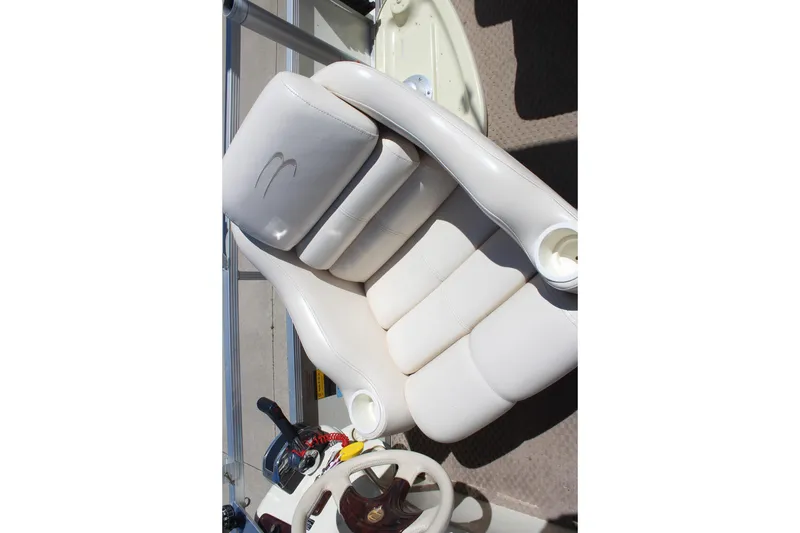 Slide: The Image of White leather seating on a 2002 Bennington 2575FS boat, featuring cup holders and steering wheel. - 19