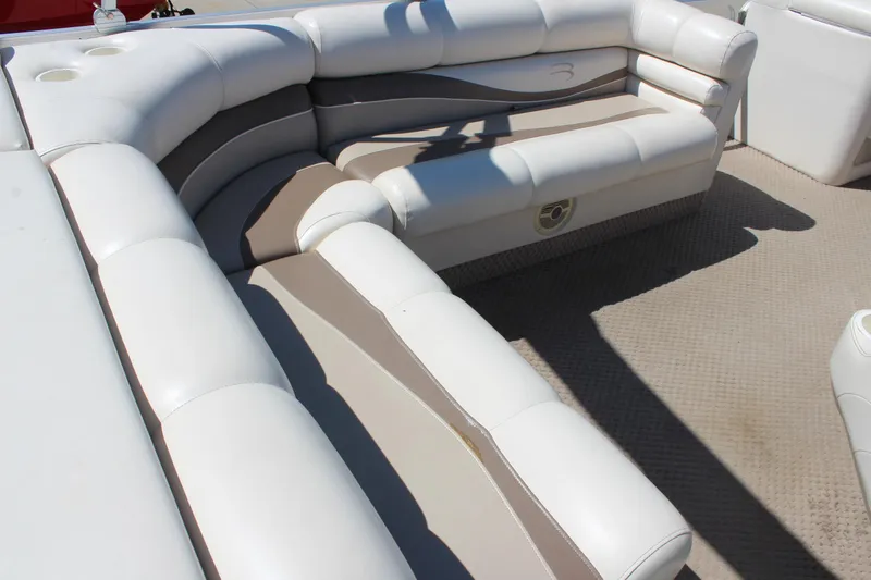 Slide: The Image of Luxurious seating on a 2002 Bennington 2575FS boat, featuring white and beige upholstery. - 21