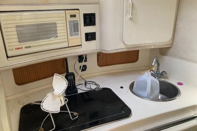 Slide: The Image of 1994 Sea Ray 290 Sundancer boat kitchen with microwave, stove, and sink. - 3