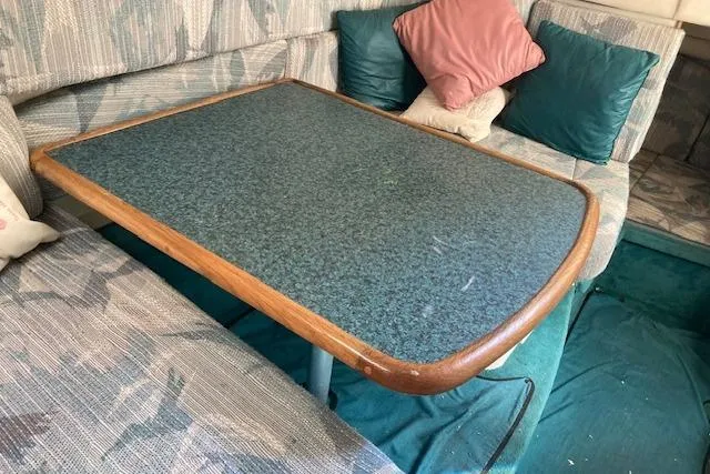 Slide: The Image of Interior seating area of a 1994 Sea Ray 290 Sundancer with a table and cushions. - 4