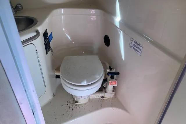Slide: The Image of Compact bathroom in 1994 Sea Ray 290 Sundancer boat, featuring a toilet and sink. - 6