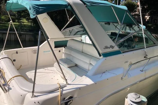 Slide: The Image of 1994 Sea Ray 290 Sundancer boat with teal canopy and white seating, docked in sunlight. - 8