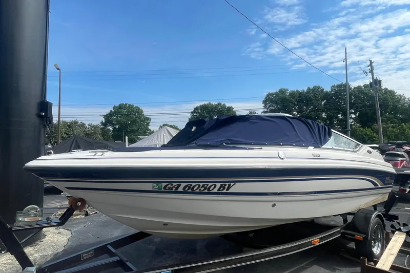 The Image of 1999 Chaparral 1830 SS boat on trailer, covered, outdoors under blue sky. - 1