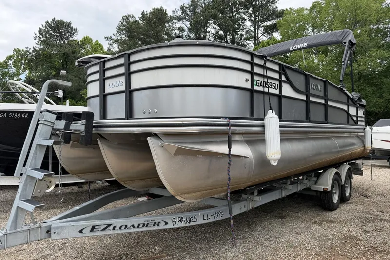 The Image of 2018 Lowe RETREAT 250 RFL pontoon boat on EZ Loader trailer, parked outdoors. - 0