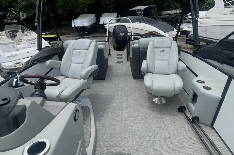 Slide: The Image of 2018 Lowe Retreat 250 RFL pontoon boat interior with plush seating and steering console. - 3