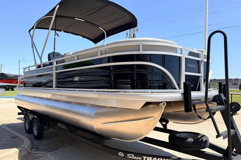 Slide: The Image of 2026 Sun Tracker SportFish 22 DLX pontoon boat on trailer, parked outdoors. - 4