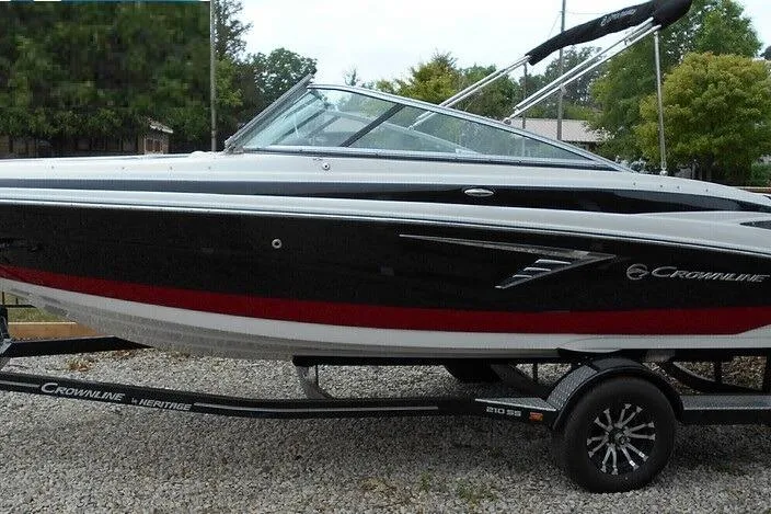 The Image of 2024 Crownline 210 SS boat on trailer, black and red design, parked outdoors. - 0