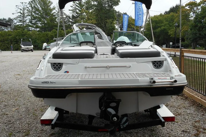 Slide: The Image of 2024 Crownline 210 SS boat, rear view, parked on gravel, showcasing sleek design and features. - 2