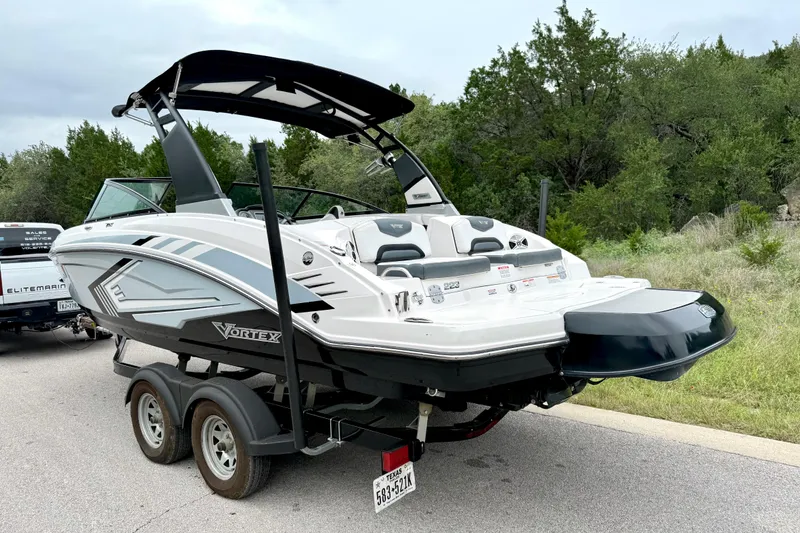 Slide: The Image of 2019 Chaparral Vortex 223 VRX boat on trailer, parked near greenery. - 15