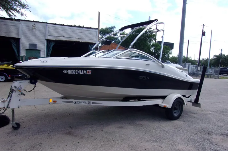 The Image of 2007 Sea Ray 185 Sport boat on trailer, parked outdoors near a warehouse. - 1