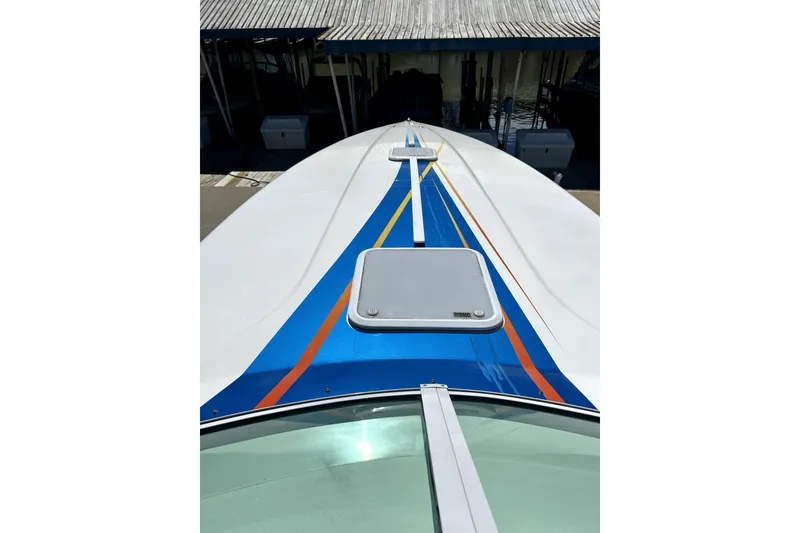 Slide: The Image of 2007 Sunsation 32 Dominator boat with vibrant blue and orange deck design. - 29