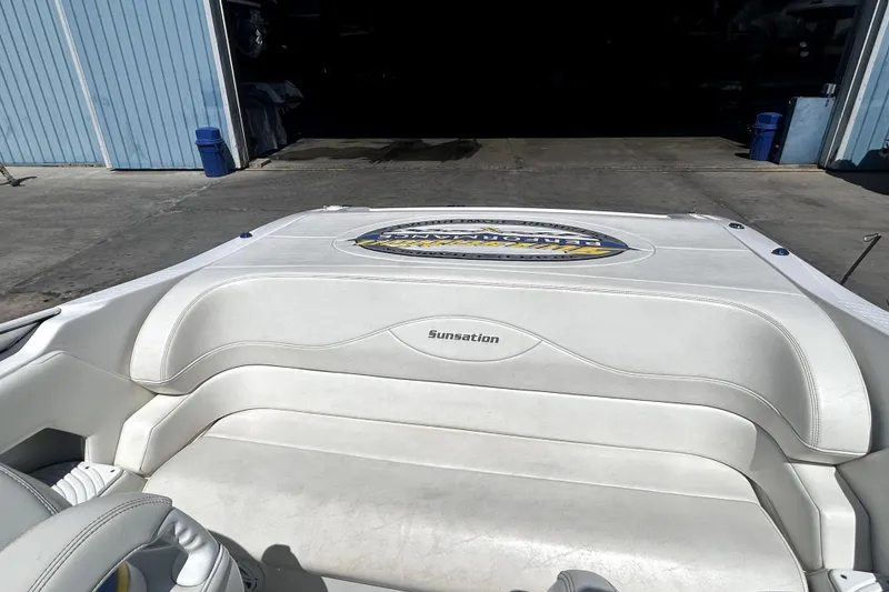 Slide: The Image of 2007 Sunsation 32 Dominator boat with white seating, docked near a blue building. - 8