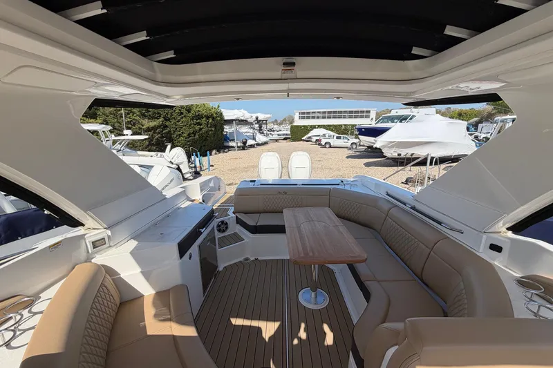 Slide: The Image of 2023 Sea Ray SLX 350 Outboard interior with luxurious seating and wooden table. - 12