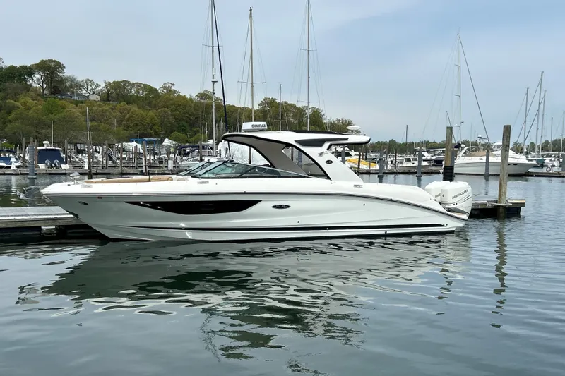Slide: The Image of 2023 Sea Ray SLX 350 Outboard boat docked in a marina with sailboats. - 2