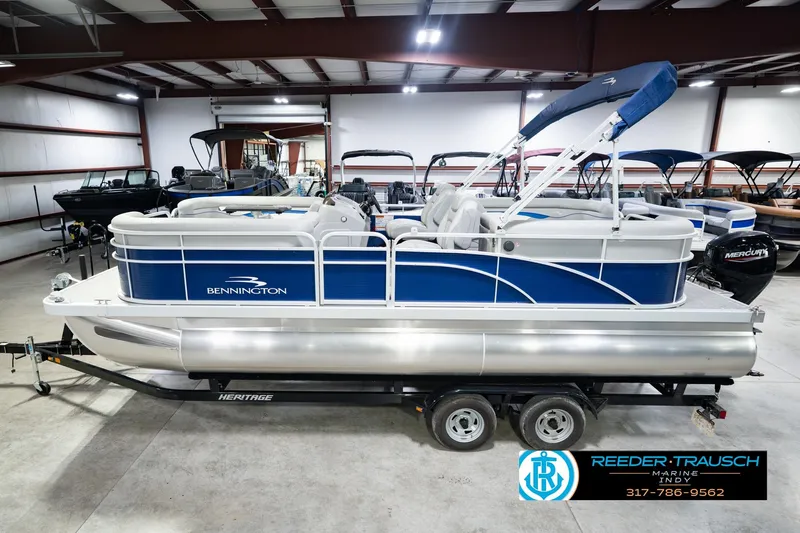 The Image of 2021 Bennington 22 SVSR pontoon boat in showroom, blue and white design, on trailer. - 0