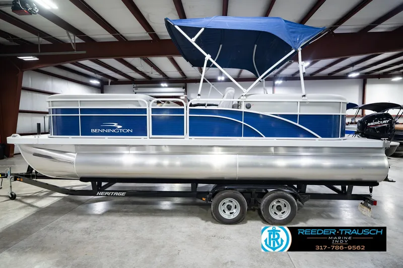 Slide: The Image of 2021 Bennington 22 SVSR pontoon boat with blue canopy in indoor showroom. - 12
