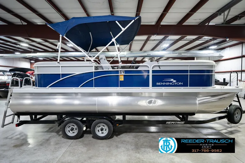 Slide: The Image of 2021 Bennington 22 SVSR pontoon boat with blue canopy in indoor showroom. - 6