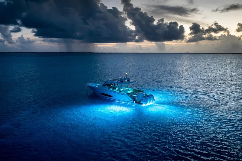 Slide: The Image of 2026 Regal 43 SAV yacht illuminated on ocean at dusk, under dramatic cloudy sky. - 30