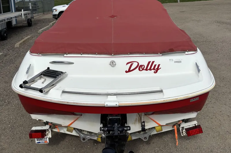 Slide: The Image of 1993 Larson SEi 200 Cuddy I/O boat with red cover, named "Dolly," parked on gravel. - 28