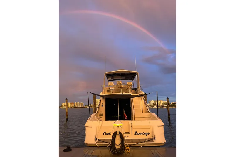 Slide: The Image of 1996 Sea Ray 550 Sedan Bridge yacht docked under a vibrant rainbow at sunset. - 2