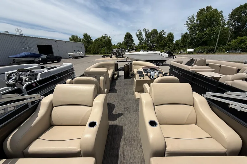 Slide: The Image of 2022 Crest Classic LX 220 pontoon boat with beige seating, parked outdoors. - 6