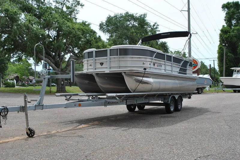 Slide: The Image of 2018 Trifecta 2.75 pontoon boat on trailer, parked outdoors with trees in background. - 3
